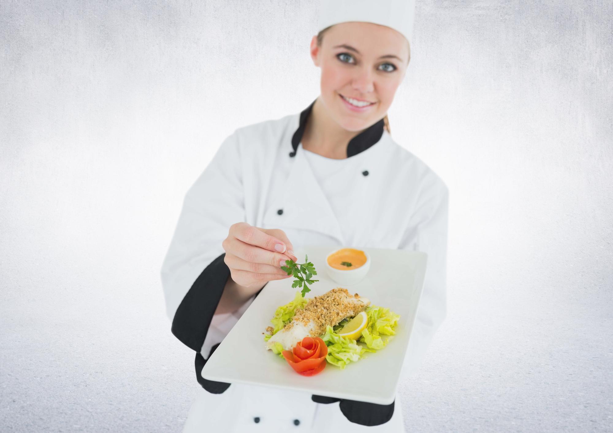 Student plating a dish under chef supervision